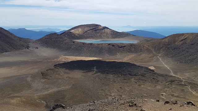 095-Tongariro-Northern-Circuit-dag-1-028.jpg - Vanop de top van de Red Crater zien we in de verte Blue Lake.